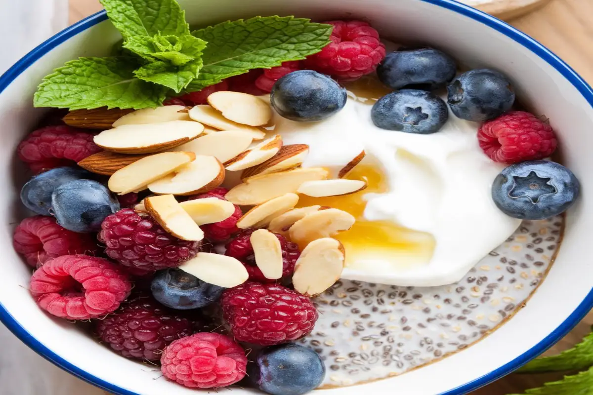 A variety of vibrant breakfast bowls with fresh fruits, grains, and toppings on a wooden table.